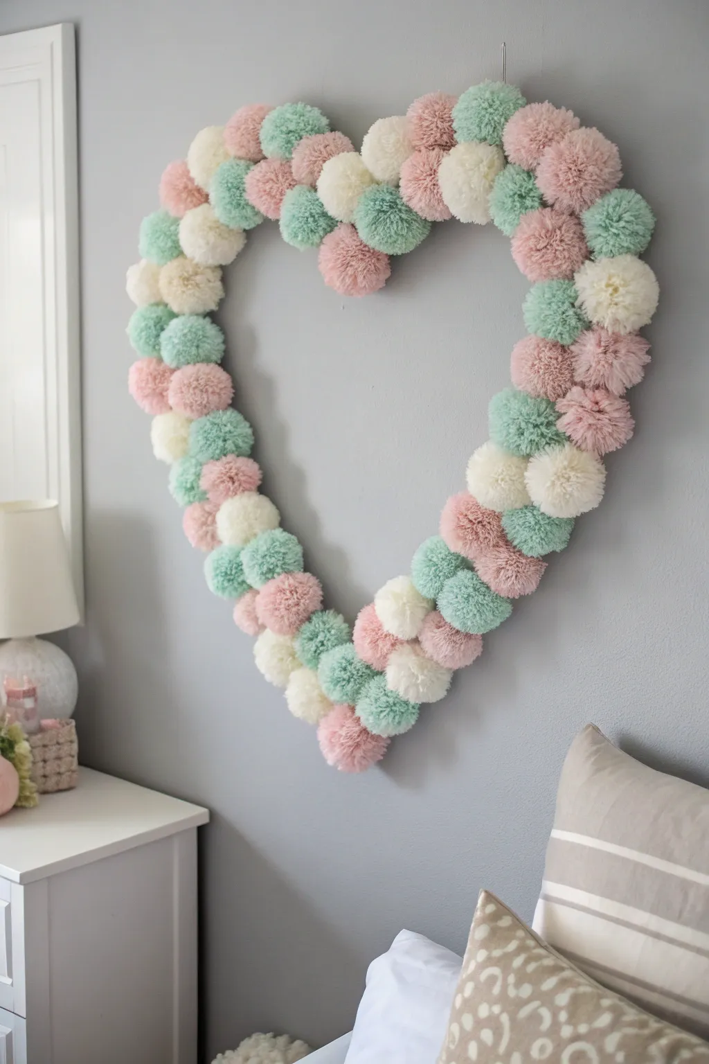 Add a touch of whimsy to your walls with a charming pom-pom heart, where minimalist design meets boho beauty.