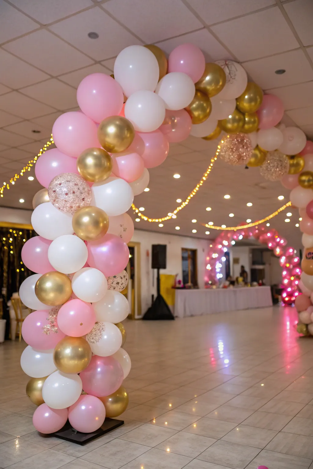 Extravagant balloon arrangements in pink, gold, and white create an inviting entrance for a sweet 16 party.