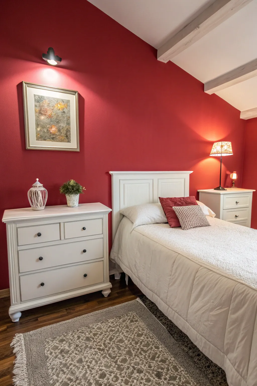 A bold red accent wall adds depth and character to a serene white bedroom.