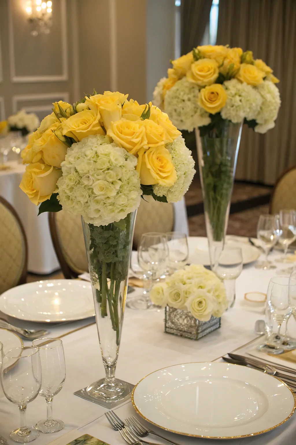 Classic elegance with yellow roses and hydrangeas in tall vases.