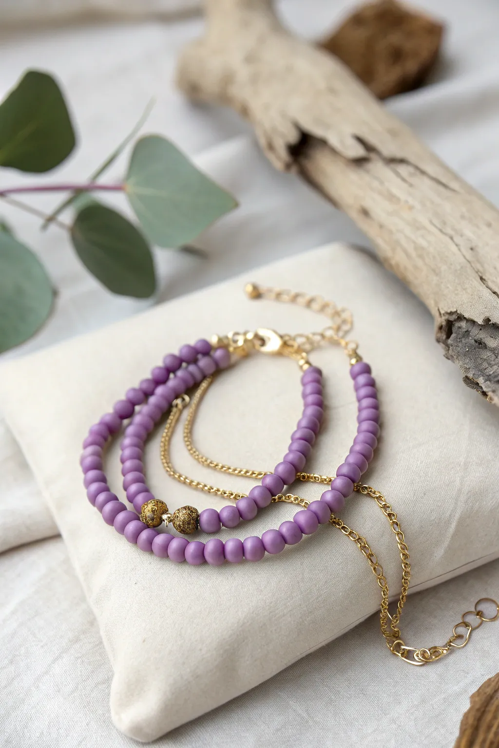 Embrace the art of layering with this elegant purple clay bead and gold chain bracelet.