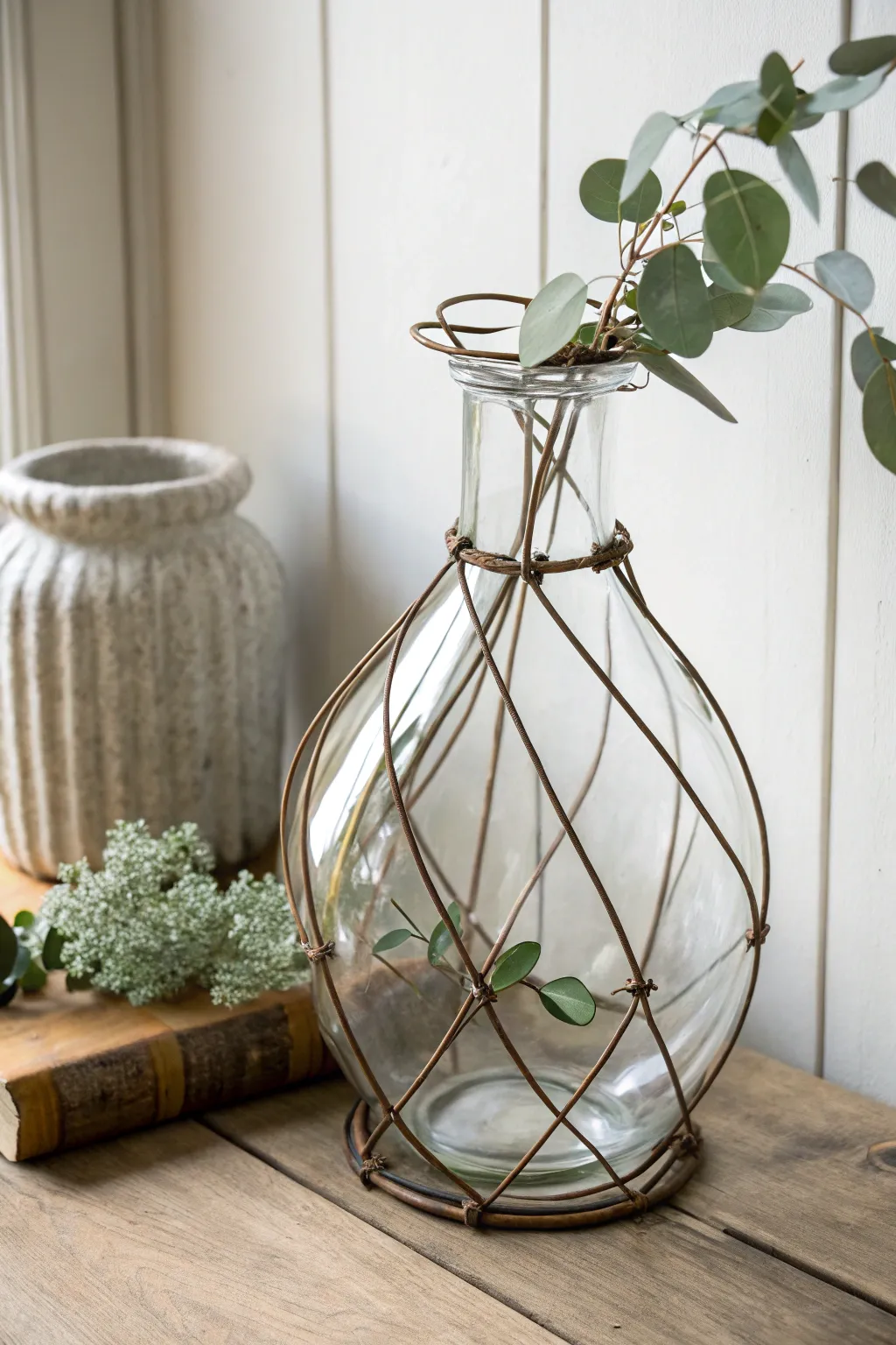 Elevate your space with a clear glass vase wrapped in industrial wire for a chic, minimalist look.