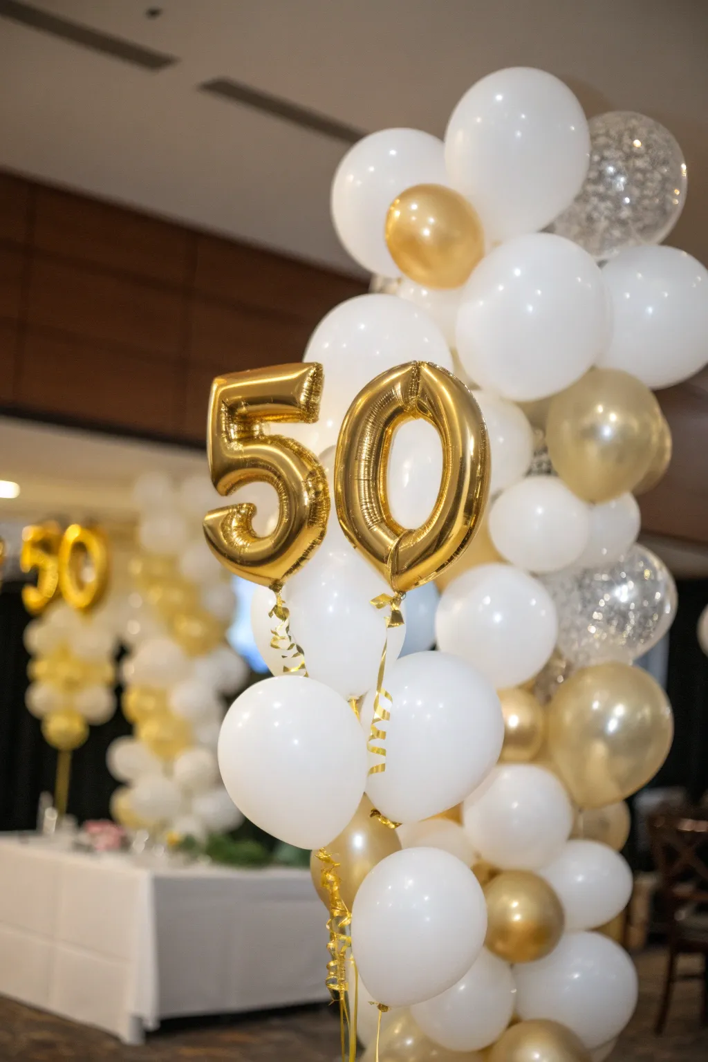 A striking gold and white balloon arrangement with the number '50' as the centerpiece.