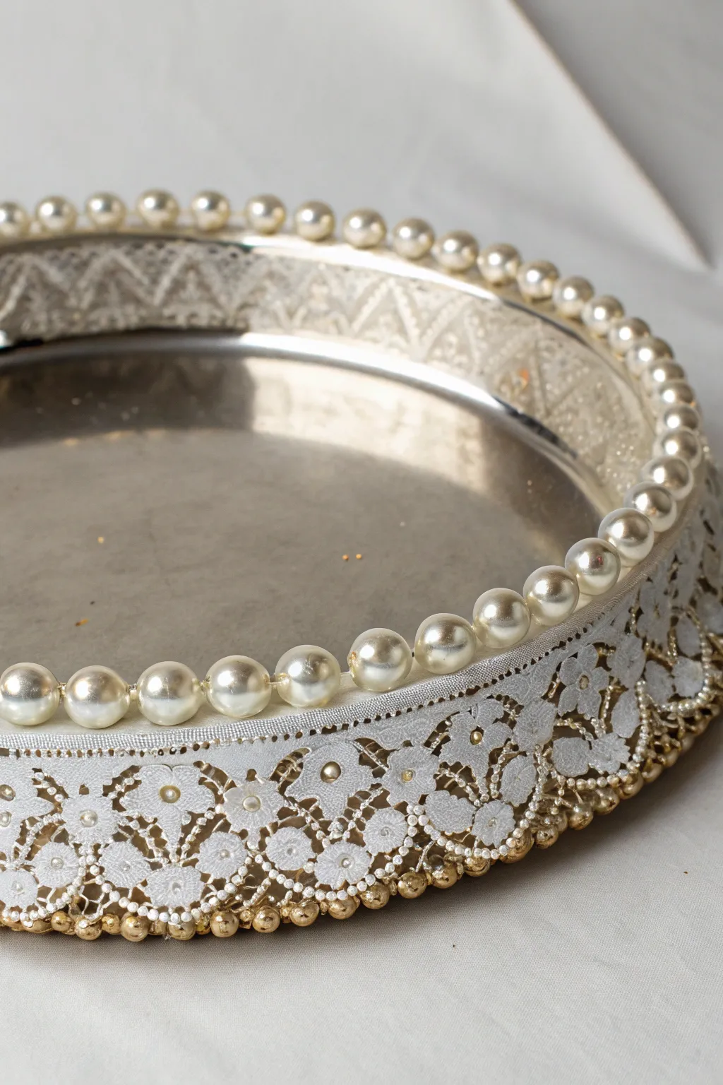 A thali rim adorned with delicate lace and beadwork.