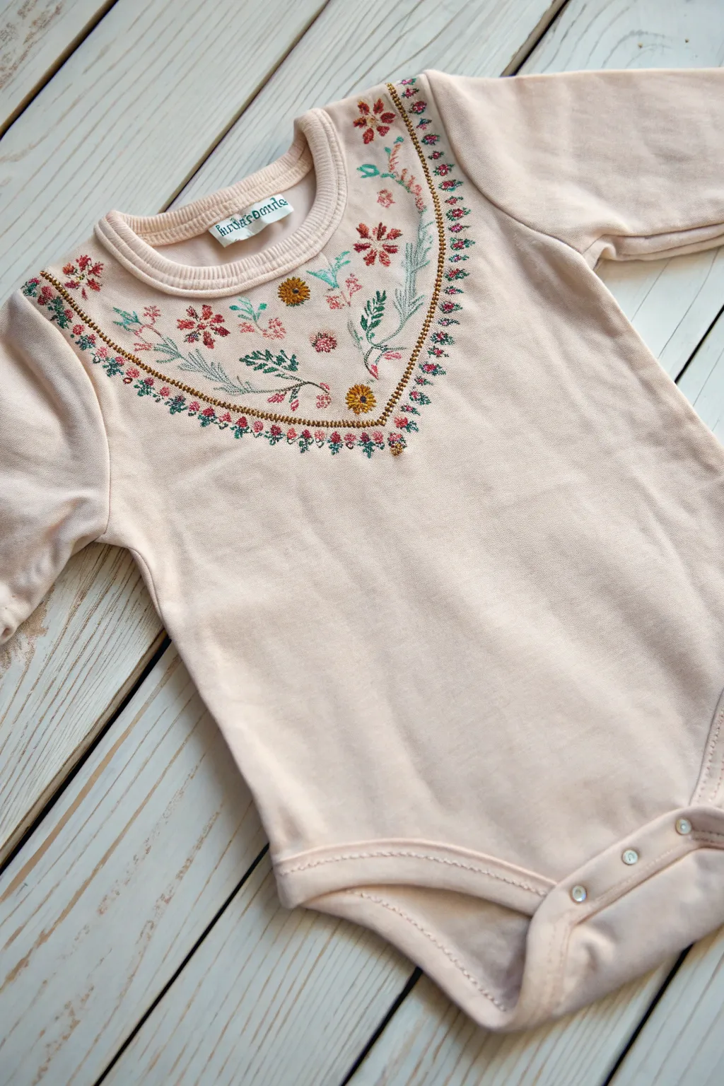 Transform a simple onesie with elegant embroidered borders for a touch of boho-chic charm.